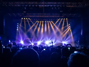 Close up on a handheld smartphone filming a concert. Stage lights are visible in the background.